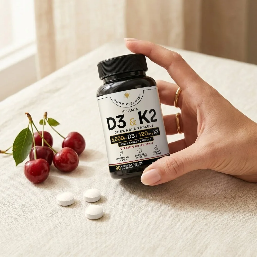 Hand holding a bottle of Noon Vitamins D3 and K2 next to cherries and chewable tablets